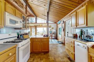 a large kitchen with white appliances and wooden cabinets at Stunning artist's retreat with ocean view & amazing deck, near Reid State Park in Georgetown