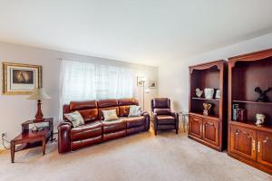 a living room with a leather couch and a chair at Idyllic waterfront home with furnished deck, grill, sweeping views & private W/D in Waldoboro