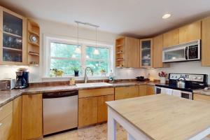 a large kitchen with wooden cabinets and a sink at Sunny coastal retreat with deck, grill, beach, dock, & ocean access in East Boothbay