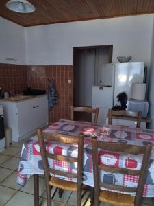 a kitchen with a table and some chairs and a refrigerator at Les sources de la Loire 2 in Sainte-Eulalie +2 photos