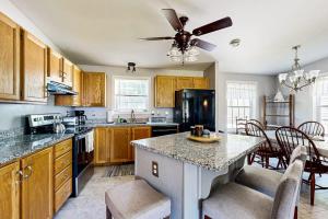a kitchen with wooden cabinets and a table with chairs at Charming cottage near the beach with balcony, deck, grill, fireplace - dogs OK in Georgetown