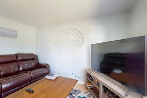 a living room with a couch and a large flat screen tv at Dog-friendly home with deck, pool table, & firepit - walk to downtown Boothbay in Boothbay Harbor
