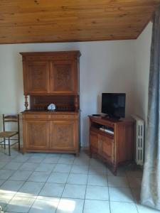 a room with a wooden entertainment center and a television at Les sources de la Loire 2 in Sainte-Eulalie