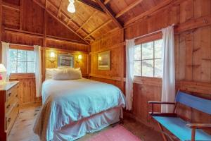 a bedroom with a bed in a room with wooden walls at Waterfront cabin with ocean view & private dock in East Boothbay