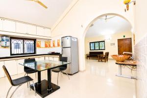 a kitchen with a table and a refrigerator at Shiva Apartments & Stud!os GOA in Parra