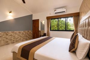 a bedroom with a large bed and a window at Shiva Apartments & Stud!os GOA in Parra