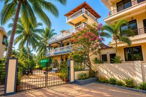 a building with a gate and palm trees at Shiva Apartments & Stud!os GOA in Parra
