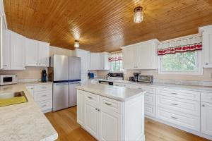 a kitchen with white cabinets and a wooden ceiling at Dog-friendly, bayfront home - gorgeous ocean views, private balcony & fireplace in East Boothbay +16 photos