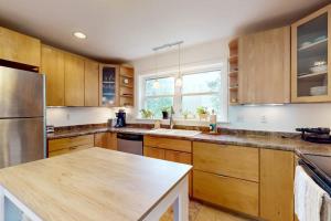 a kitchen with wooden cabinets and a stainless steel refrigerator at Sunny coastal retreat with deck, grill, beach, dock, & ocean access in East Boothbay
