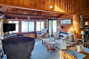 a living room with a couch and chairs and a tv at Vintage lakefront cabin with incredible water views, private dock & pebble beach in The Highlands