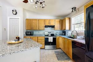 a kitchen with wooden cabinets and a stove top oven at Charming cottage near the beach with balcony, deck, grill, fireplace - dogs OK in Georgetown