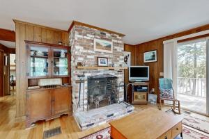 a living room with a stone fireplace and a tv at Lady Slipper Cottage: Charming Lakefront Retreat with Canoes, Kayaks, and Modern Comforts in Somesville