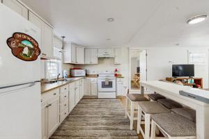 a kitchen with white cabinets and a counter with stools at Well-located, dog-friendly home - walk to footbridge & Barrett Park in Boothbay Harbor