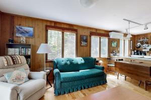 a living room with a blue couch and a piano at Lady Slipper Cottage: Charming Lakefront Retreat with Canoes, Kayaks, and Modern Comforts in Somesville