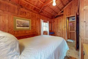a bedroom with a white bed in a wooden room at Waterfront cabin with ocean view & private dock in East Boothbay +11 photos