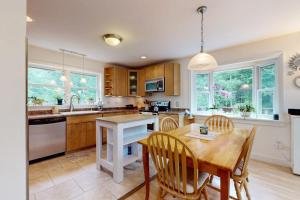 a kitchen with wooden cabinets and a wooden table and chairs at Sunny coastal retreat with deck, grill, beach, dock, & ocean access in East Boothbay