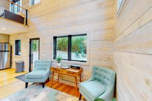 a living room with two chairs and a wooden wall at Contemporary home with woodstove, firepit, 2 kitchens & fast WiFi- walk to beach in Marlboro