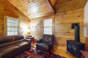 a living room with a leather couch and a stove at Charming dog-friendly studio cabin with firepit and near outdoor fun in Northport