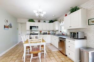 a kitchen with white cabinets and a table and chairs at Charming Lakefront House with Outdoor Firepit, Washer/Dryer and Wifi in Gouldsboro