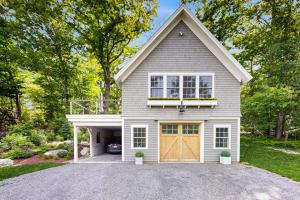 a white house with a brown garage at Brand new guest apartment with furnished deck, fast WIFI, dock, & water views in Boothbay Harbor