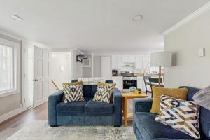 a living room with two blue couches and a kitchen at Secluded waterfront home with private dock, outdoor dining, firepit, WiFi & W/D in Orland