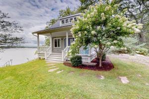 a small white house with a tree in the yard at Periwinkle Cottage | Sunny cottage in Westport Island overlooking the river in Westport