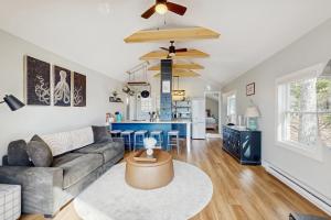 a living room with a couch and a kitchen at Charming cottage with a spacious deck overlooking the Megunticook River in Camden