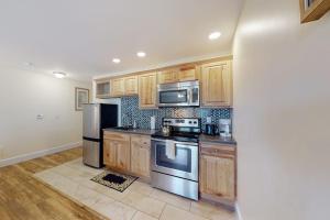 a kitchen with wooden cabinets and stainless steel appliances at Stylish Condo at Sheepscot Harbor Resort w/Free WiFi, River Views, & Balcony in Edgecomb +12 photos