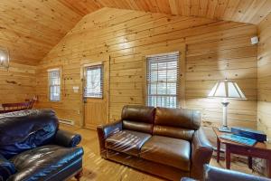 a living room with leather furniture in a log cabin at Comfortable two bedroom cabin with firepit, kitchen, hiking trail within walking in Northport