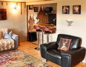 a living room with a leather chair and a bar at The Tranquil Retreat Countryside Escape in Larkhall