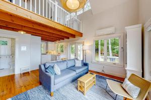 a living room with a blue couch and a staircase at Periwinkle Cottage | Sunny cottage in Westport Island overlooking the river in Westport +11 photos