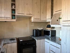 a kitchen with wooden cabinets and a stove and a microwave at SnaMel's in Waterfall