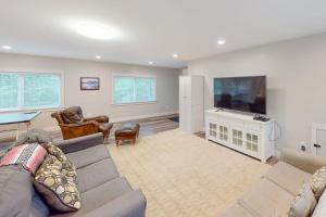 a living room with a couch and a flat screen tv at Waterfront home with deck, patio, grill, firepit, Ping-Pong, & WiFi in Somesville