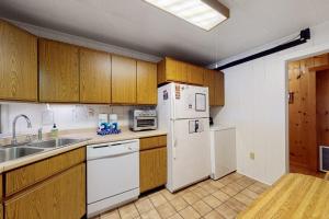 a kitchen with a white refrigerator and a sink at Lakefront Home with Private Dock, Pebble Beach & Enclosed Porch - Dogs Welcome in Greenville Junction