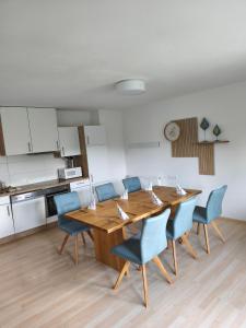 a dining room with a wooden table and blue chairs at Putz Appartements in Gröbming