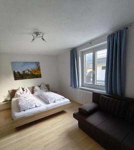 a bedroom with a bed and a couch and a window at Putz Appartements in Gröbming