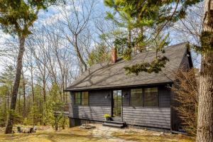 a small house in the middle of the woods at Renovated woodland home with lovely deck & firepit - minutes to Swan Lake in Swanville