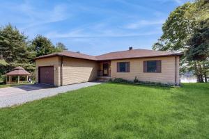 a house with a garage and a grass yard at Charming Lakefront House with Outdoor Firepit, Washer/Dryer and Wifi in Gouldsboro