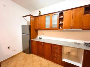 a kitchen with wooden cabinets and a stainless steel refrigerator at Cozy Village Guesthouse in Delvinë