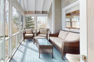 a porch with a couch and chairs and windows at Oceanfront retreat with sunrise views, screened porch, & deck in Blue Hill