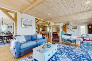 a living room with a blue couch and a table at Oceanfront home with dock, beautiful deck & firepit - steps to the beach in Harpswell Center