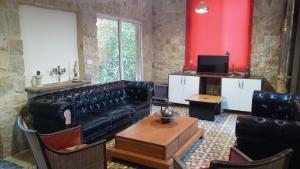 a living room with a black leather couch and a tv at Khalle Lodge in Dayr al Qamar