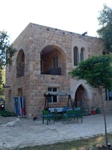 a building with two green benches in front of it at Khalle Lodge in Dayr al Qamar