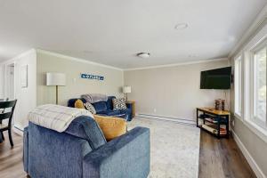 a living room with a blue couch and a tv at Secluded waterfront home with private dock, outdoor dining, firepit, WiFi & W/D in Orland