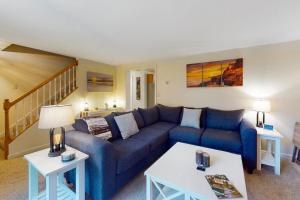 a living room with a blue couch and two tables at Serene home with a deck, grill, firepit, board games, washer/dryer, & mtn views in East Lamoine