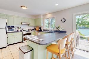 a kitchen with green cabinets and a counter with chairs at Water-view retreat with beach access, deck, grill, EV charger & lawn games in North Harpswell +25 photos