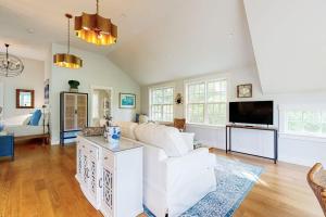 a living room with a white couch and a tv at Brand new guest apartment with furnished deck, fast WIFI, dock, & water views in Boothbay Harbor