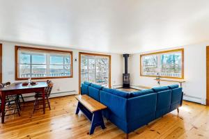a living room with a blue couch and a table at Dog-friendly river-view home with wood stove, deck, patio, dock, beach, grill in Boothbay