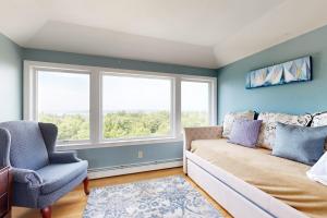 a bedroom with a couch and a chair and windows at Expansive Modern Home w/ Ocean View, Gorgeous Garden & Dog-friendly in East Boothbay