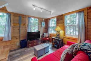 a living room with a red couch and a television at 2 beautifully designed, off-the-grid homes with amazing lakefront views & access in Franklin +44 photos